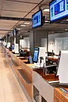 Leere Check-in-Halle mit Schaltern, Selbstbedienungskiosk und digitalen Anzeigen