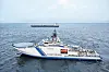 Ein Boot auf dem offenen Meer, im Hintergrund ein Öltanker