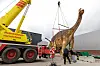 Ein Kran hebt die Dinosaurier-Dame „eLise“ auf einem Industriegelände für den Transport nach Damme an.