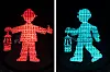 Leuchtendes Bergmann-Ampelmännchen in Rot und Türkis mit Grubenlampe vor schwarzem Hintergrund