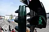 Leuchtende Karl-Marx-Figur an einer Fußgängerampel in Trier, daneben Straßenverkehr und wartende Passanten.