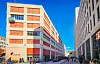 Haus der Erde der Universität Hamburg am Schlump zwischen modernen Gebäuden, mit Passanten unter blauem Himmel