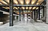 Weite Industriehalle der Maschinenzentralstation mit Stahlstützen, Betonboden und Foyer im Hintergrund