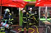 Einsatzkräfte der Feuerwehr treten aus einem Imbiss heraus