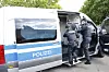 Polizisten führen einen Mann in Handschellen ab.