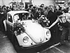 Menschen beugen sich zu einem geschmückten VW Käfer