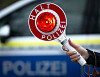 Eine Polizistin hält während einer Verkehrskontrolle eine Polizeikelle mit der Aufschrift „Halt Polizei“. (Symbolbild)