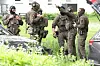 Polizeibeamte in Spezialausrüstung stehen vor einem Hochhausn und beratschlagen sich.