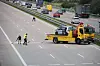 Das bei dem Unfall zerstörte Auto wird abgeschleppt, Beamte reinigen die Fahrbahn