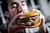 Ein Mann isst einen Burger.