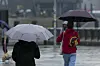 Touristen mit Regenschirmen unterwegs im Regen an den Landungsbrücken im Hafen von Hamburg