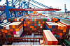 Container werden im Hafen mit einem Kran von einem Schiff gehoben.