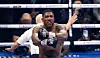 Der Boxer Anthony Joshua posiert, während der Ringrichter im Hintergrund seinen Gegner anzählt