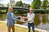 Bezirksamtsleiter Michael Werner-Boelz (Grüne, r.) und Kai-Uwe Jacobsen vom Fachamt Management des öffentlicher Raums stellen die neuen Schilder vor. Im Hintergrund springen Jugendliche von der Brücke ins Wasser.