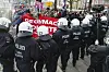 Eine Reihe an uniformierten Polizisten steht vor einer Gruppe Demonstranten