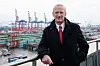 Mann mit rroter Krawatte vor Hafenkränen