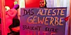 Eine Prostituierte hält in der Herbertstraße ein Schild mit der Aufschrift „Das älteste Gewerbe der Welt braucht Eure Hilfe“.
