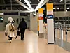 Reisende laufen im Terminal 2 an Schildern vorbei, die auf den Check-In-Bereich der Lufthansa hinweisen