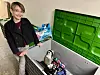 Eine Schülerin steht vor einer großen Kiste mit Elektroschrott