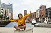 Happy young woman with arms outstretched sitting on bench at Elbphilharmonie model released, Symbolfoto, IHF01157