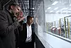 Peter Carlsson gestikuliert mit Robert Habeck, der durch ein Fenstern in eine Fabrik schaut.