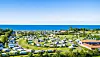 Das „Insel-Camp“ auf Fehmarn. Im Hintergrund ist blauer Himmel und blaues Meer. Man sieht viele weiße Wohnwagen/ Wohnmobile.