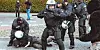 Ein Polizist drückt einen Mann zu Boden. Seine Kollegen halten die Demonstranten ab.