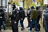 Polizisten und andere Personen verlassen das Anwesen eines Gebäudes in Neukölln.