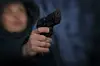 Ein Mensch hält eine Waffe, das Bild ist unscharf (Symbolfoto).