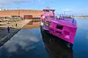 Eine knallig pinke Hybrid-Fähre liegt vor der Werfhalle der Schiffbau- und Entwicklungsgesellschaft Tangermünde (SET) im Wasser.