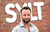 Dirk Lins steht vor einem Sylt-Schriftzug