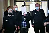 Ein Angeklagter wird zu Beginn des Prozesses von drei Justizbeamten mit Handschellen in den Gerichtssaal begleitet. (Archivbild)