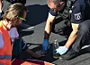 Ein Berliner Polizeibeamter löst mit Sonnenblumenöl die festgeklebte Hand eines Klimaschutz-Demonstranten der Gruppe „Letzte Generation“ vom Asphalt (Archivbild).
