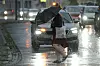 Eine Frau läuft mit einem Regenschirm über eine Straße