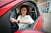 Eine Frau am Steuer eines roten Autos.
