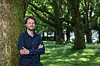 Torsten Melzer lehnt mit verschränkten Armen an einem Baum.