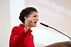 Schwazhaarige Frau in roter Jacke an Mikrofon