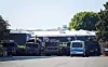Ein Polizeifahrzeug steht vor mehreren verbrannten Militärlastern auf dem Gelände eines Nutzfahrzeug-Serviceunternehmen.