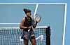Naomi Osaka klatscht auf ihren Tennisschläger und lacht
