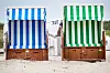Ein blauer und ein grüner Strandkorb stehen nebeneinander.