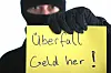 Maskierter Mann hält eine Schild mit dem Schriftzug - Überfall - Geld her!