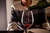 Eine Frau gießt zuhause Wein in ein Glas.