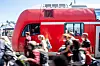 Regionalzug steht am Bahnhof, Menschen laufen über das Gleis.