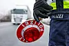 Ein Polizist hält eine Polizeikelle für eine Kontrolle an der Autobahn.
