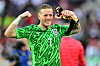 Jordan Pickford jubelt im grünen England-Trikot vor unscharfem Stadionhintergrund.