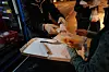 Eine ehrenamtliche Helferin des Mitternachstbusses für obdachlose Menschen, überreicht in der Innenstadt einer Frau ein Stück Pizza.
