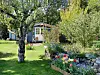 ein Kleingarten: blau gestrichene Gartenlaube, im Vordergrund ein Obstbaum, daneben Blumenbeete