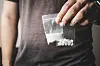 Ein Mann hält zwei Tütchen mit Drogen in der Hand. (Symbolfoto)