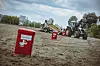 Elbstrand: rote Mülleimer und ein neuer „Beachcleaner“: ein Traktor zieht ein großes Reinigungsgerät.