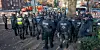 Die Polizei vor einer Gruppe schwarz gekleideter Demonstranten.